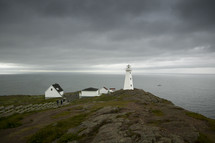 lighthouse along a shore under gray skies 