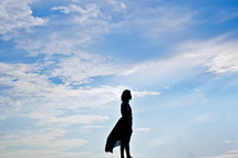 a silhouette of a woman standing with open arms 