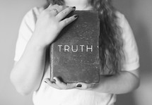 woman holding a book with the word Truth 