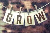 The word "grow" spelled out on cards hooked to string with clothespins.
