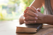 praying hands on the cover of a Bible 