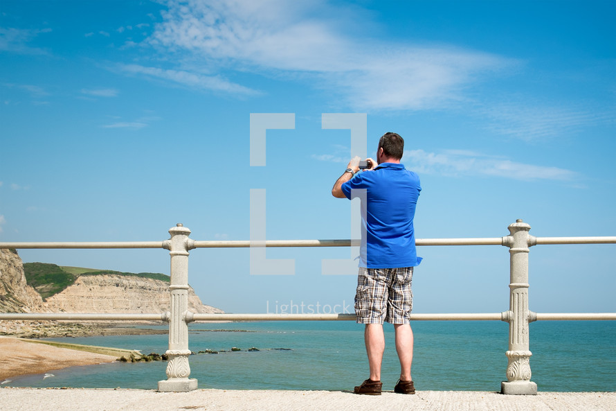 man taking a picture over a railing 