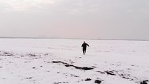 exhausted man running through a snow covered landscape 