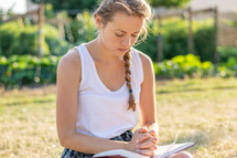 a woman reading a Bible outdoors and praying 