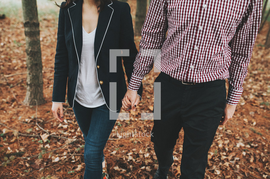 a man and woman walking outdoors in fall holding hands 