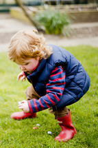 Child finding Easter eggs in the grass.