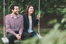 a happy couple sitting on a swing 