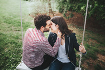 a couple kissing on a swing 