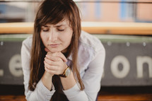 a young woman with praying hands and closed eyes 