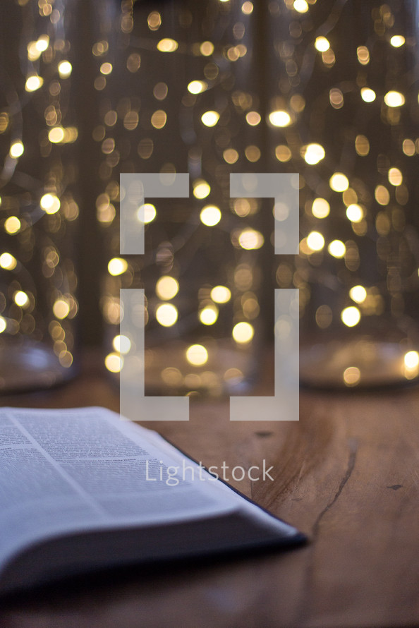 open Bible on a floor in front of bokeh lights from a Christmas tree 