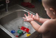 an infant playing in a sink 