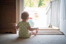 an infant sitting in front a door 