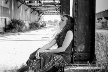 woman sitting under a bridge 
