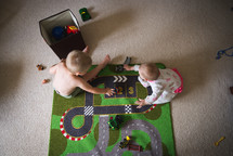 a toddler and infant playing with toys on the floor 