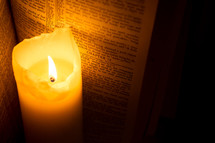 Burning candle next to a Bible open to Hebrews 12.