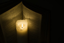Burning candle next to a Bible open to Hebrews 11.