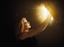 woman holding up a glowing Bible