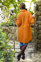 A young woman in a sweater standing between gates orange