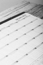 Day planner open to January 2013 on wooden table.
