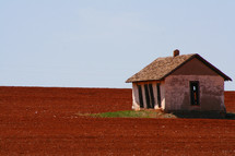 old barn in a red dirt field 