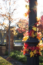 decorative fall leaves around an outdoor lamp post 