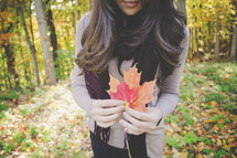 a woman holding fall leaves 