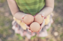 Child holding three eggs.