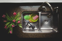 dirty dishes in a sink and flowers 