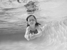 a child in goggles swimming under water 