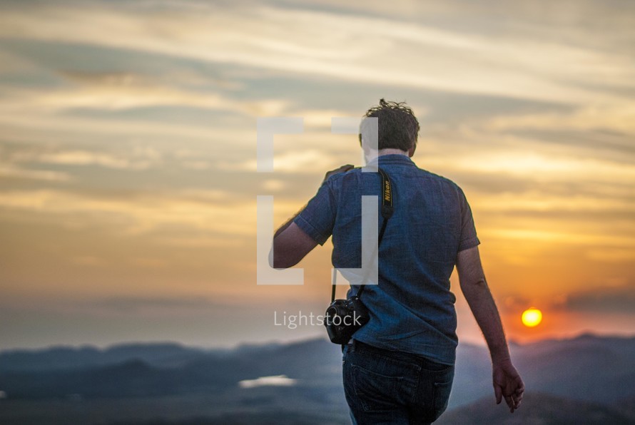 a man walking with his camera at sunset 