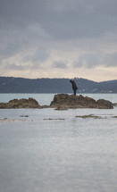 man standing on rocks in shallow water 