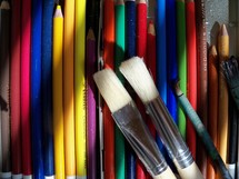 A set of colored pencils and varying sizes of paint brushes reflect an array of colors for an artist to crate illustrations, paintings, drawings and sketches to create a palette of colors to create a new piece of art.