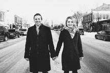 a couple holding hands standing in the middle of a street