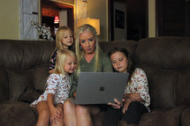 a mother looking at a computer screen with her daughters 