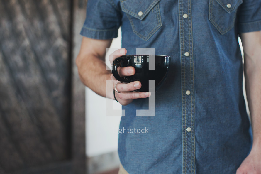 torso of a man holding a mug
