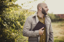 man holding a Bible outdoors