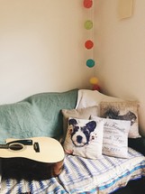 throw pillows and acoustic guitar on a couch 
