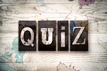 word quiz on a white wash wood background 