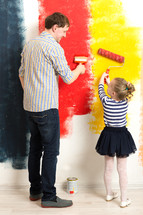 Father and daughter painting wall