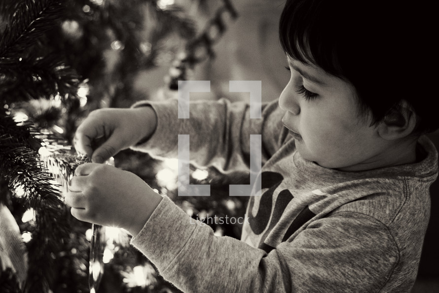 a boy child decorating a Christmas tree 