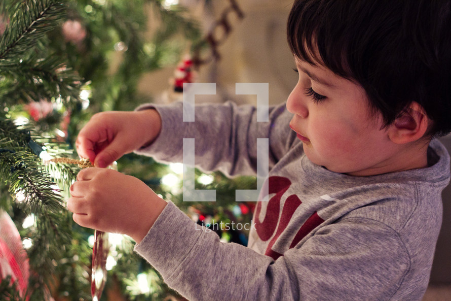 boy child decorating a Christmas tree 