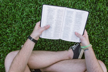 man reading a Bible in the grass 