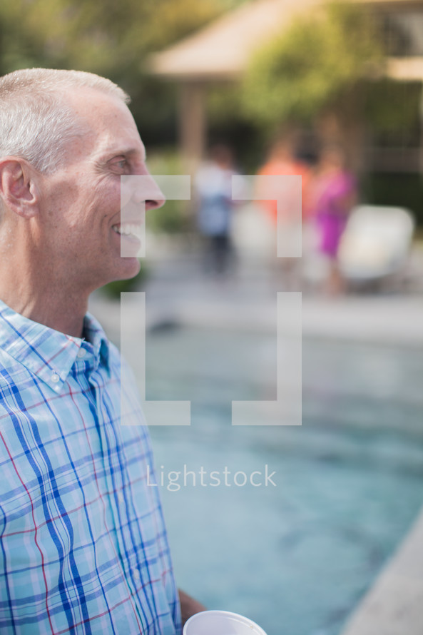 man standing by a pool at an outdoor summer party 