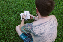 man with back tattoos reading a Bible 