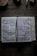 notes on the pages of a Bible on a workbench 