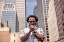 An African American man in prayer in a city 