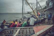 people and boats on the shore of a fishing village 