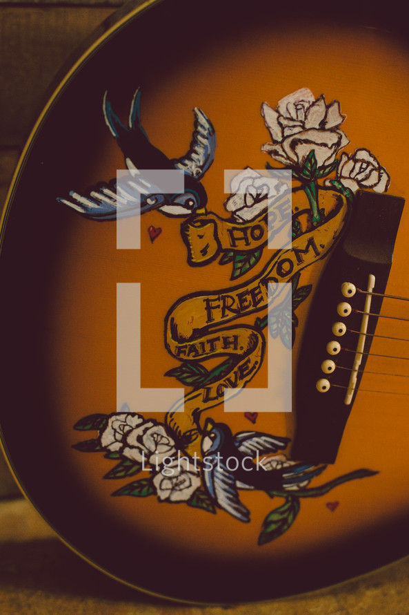 "Hope, freedom, faith, love" emblem on an acoustical guitar.