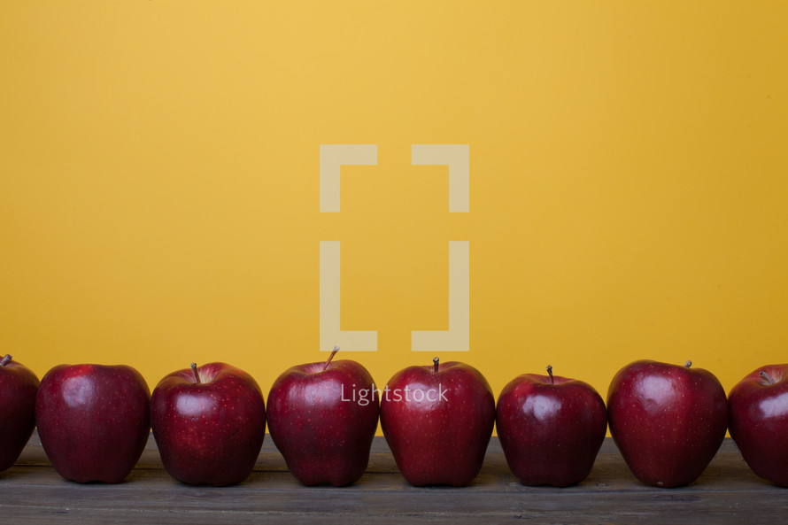 row of apples on a wood table 