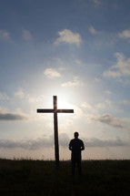 a man praying in front of a cross